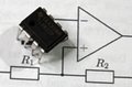 An op-amp placed on top of a circuit diagram showing an operational amplifier with resistors R1 and R2.
